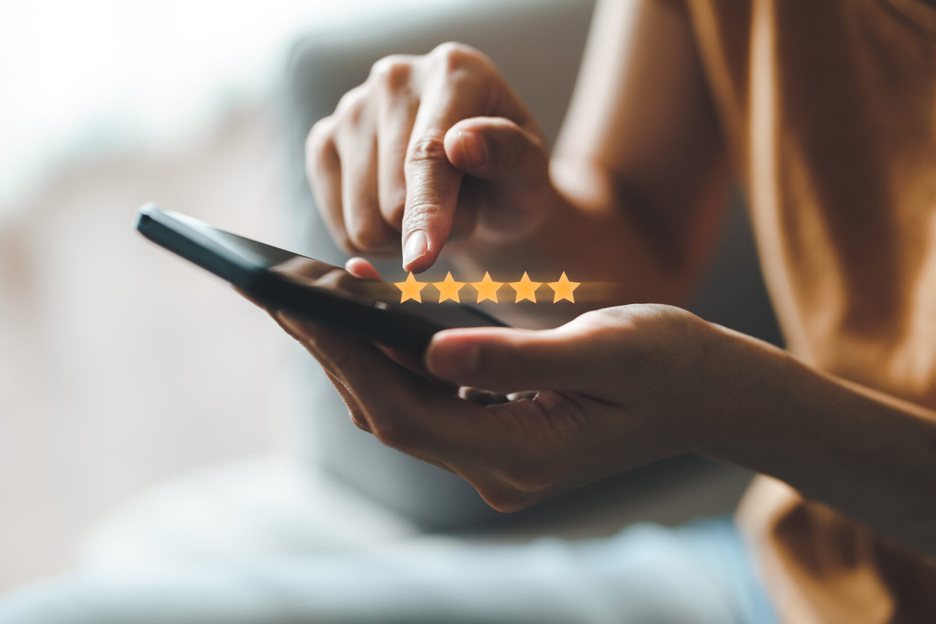 An image of a person giving a five-star review on their phone.