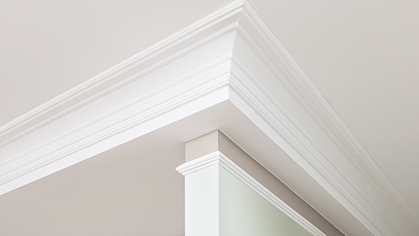 An image of white crown moulding in a tan living room